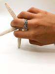   Anillo de plata de ley, de superficie labrada con motivos inspirados en la flor de lis, símbolo de honor y lealtad. 