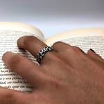   Anillo de plata de ley, de superficie labrada con motivos inspirados en la flor de lis, símbolo de honor y lealtad. 